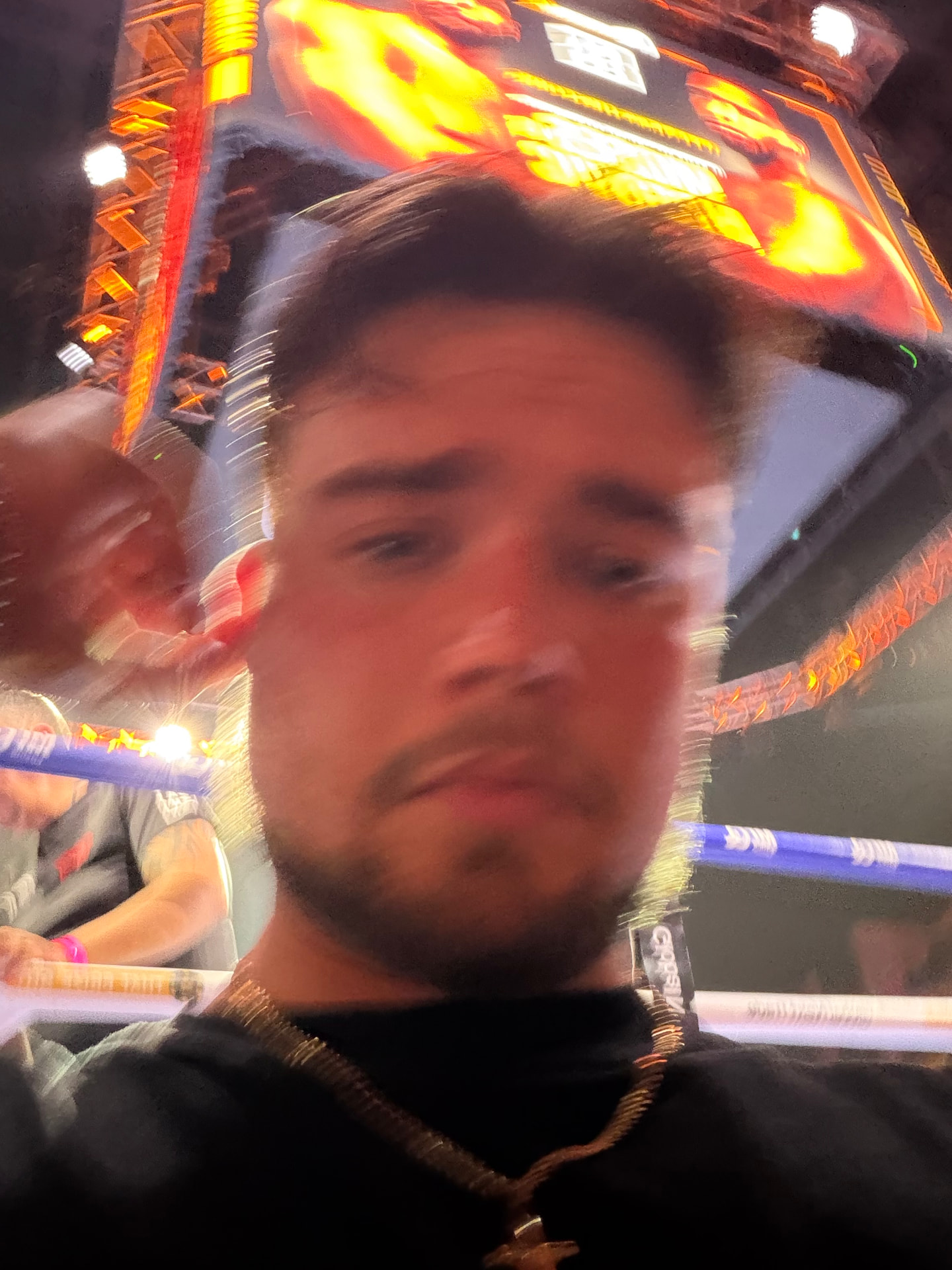 Mitch Mottram ringside on fight night, arena big screen and ring lights behind him, filming for the Derek Chisora Kick stream